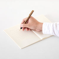 Hand holding a pen over an open notebook on a white surface